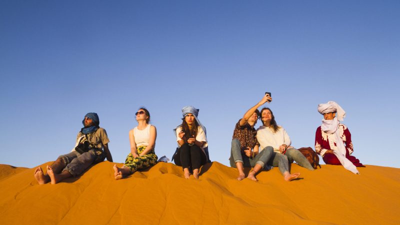 group-of-people-sitting-on-top-of-dune